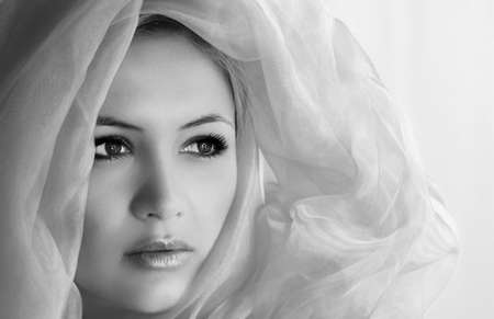 beauty portrait of a young and beautiful woman with a shawl on her headの写真素材