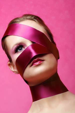 beauty portrait of a young woman in pink with wrapped ribbon