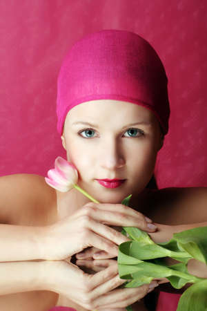 beauty portrait of a young woman in pink with a tulip flower on a mirrorの写真素材