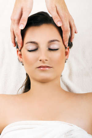 young beautiful woman in a spa is getting a massage on her faceの写真素材