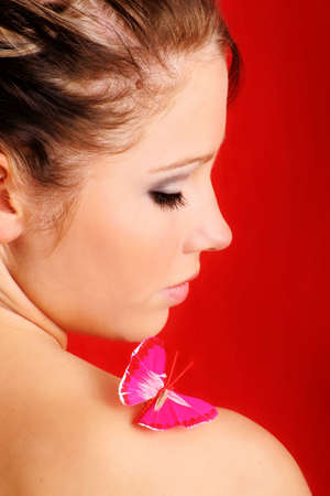 beauty portrait of a beautiful young woman with a butterfly on her shoulderの写真素材