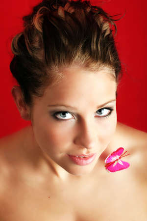 beauty portrait of a beautiful young woman with a butterfly on her shoulderの写真素材