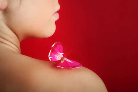 beauty portrait of a beautiful young woman with a butterfly on her shoulderの写真素材