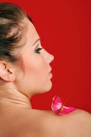 beauty portrait of a beautiful young woman with a butterfly on her shoulderの写真素材