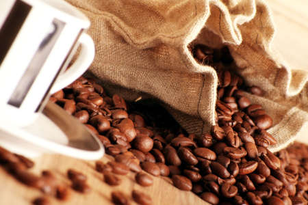 some coffee beans and a jute sack behind a cup of black coffee