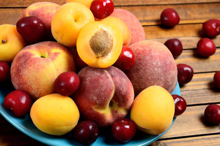 Blue plate with variety fruits on wooden tableの写真素材
