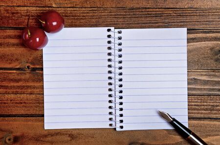 Cherries with empty notepad on table