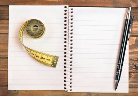 Notepad with centimeter and pen on wooden tableの写真素材