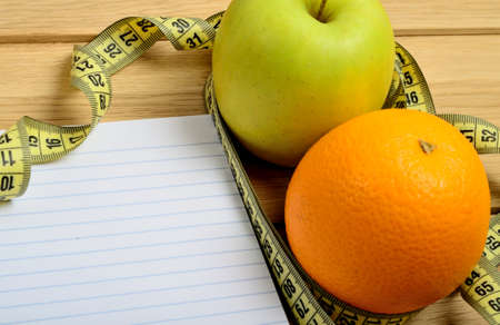 Notebook with apple and orange fruit on tableの写真素材