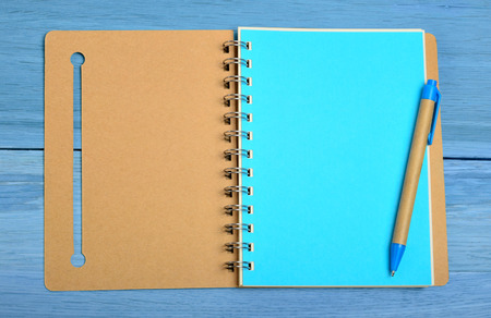 Open notebook with pen on blue wooden tableの写真素材