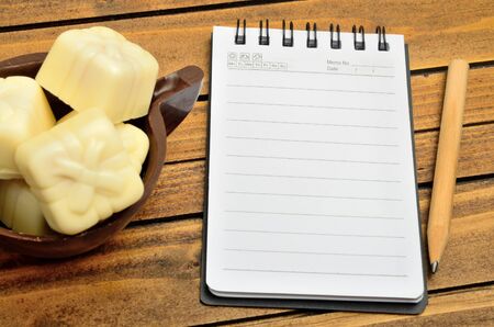 Notebook with chocolate gift on wooden tableの写真素材
