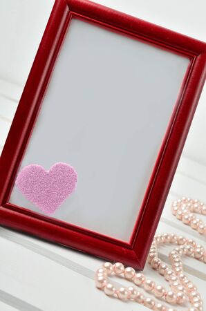 Frame photo with heart shape and pearl on wooden tableの写真素材