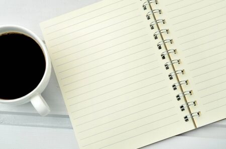 Cup of coffee with notebook on tableの写真素材