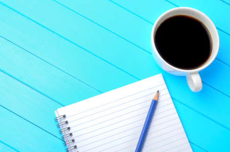 Notepad with pencil and coffee on blue wooden tableの写真素材