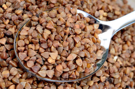 Buckwheat groats in metal spoon on tableの写真素材