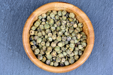 Bowl with green peppercorns on slateの写真素材
