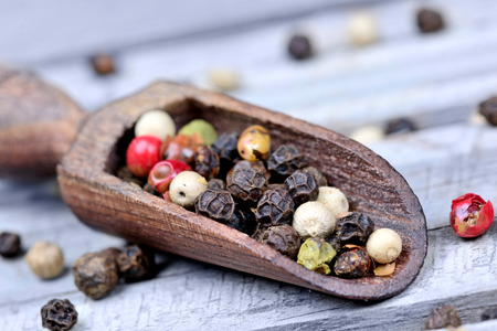 Colorful peppercorns in a wooden scoop on wooden table
