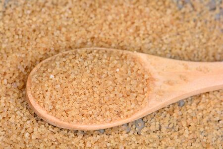 Beige sugar in a wooden spoon on tableの写真素材