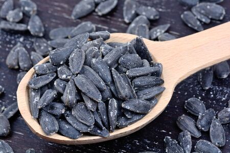 Wooden spoon with black sunflower seeds on tableの写真素材