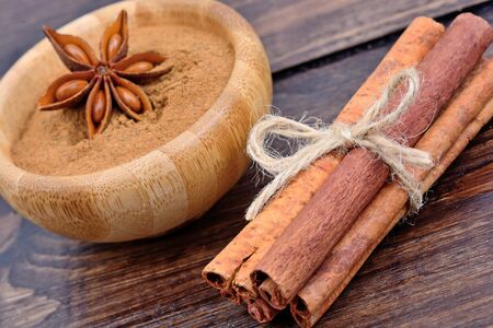 Cinnamon sticks and bowl with cinnamon powder on wooden tableの写真素材