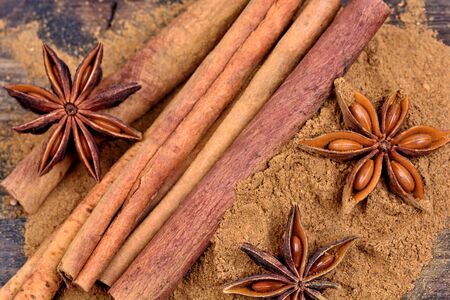 Cinnamon sticks and powder with star anise on wooden table
