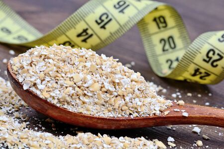 Wooden spoon with oat and centimeter on tableの写真素材