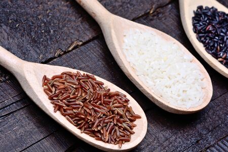 Various types of rice in a wooden spoons on tableの写真素材