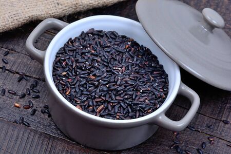 Black rice in a pot on wooden tableの写真素材