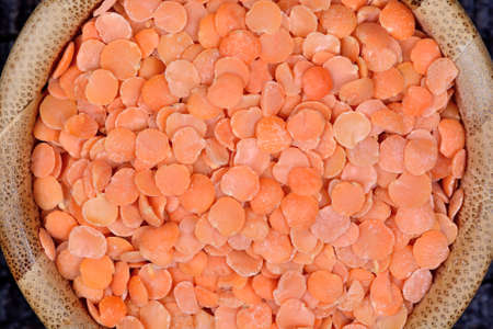 Red lentils in a bamboo bowl on tableの写真素材