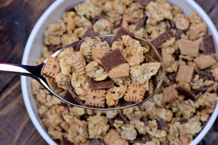 Muesli with chocolate in a spoon and bowl on wooden table