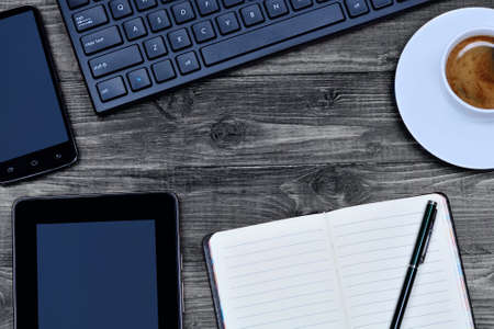 Notebook with digital tablet, phone and coffee on wooden table