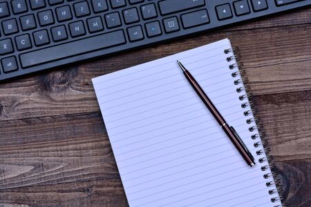 Notepad with keyboard computer on wooden tableの写真素材