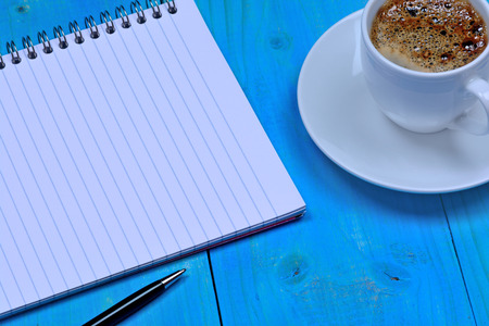 Notebook with pen and coffee on desk close-upの写真素材