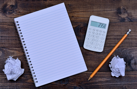 Notebook with pencil and calculator on wooden tableの写真素材