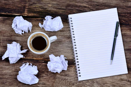 Notepad with pen coffee and crumpled paper on desk close-upの写真素材