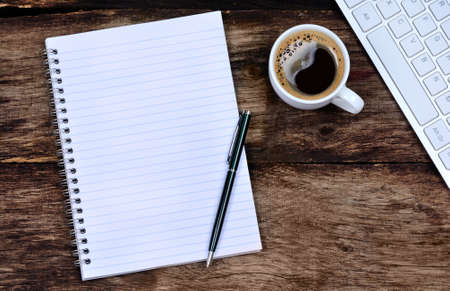 Empty notebook with coffee and keyboard computer on deskの写真素材