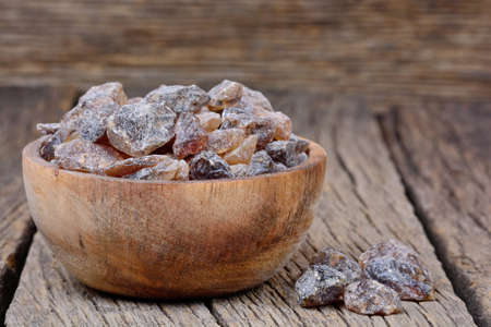 Brown candy crystals in a bowl on wooden table close-upの写真素材