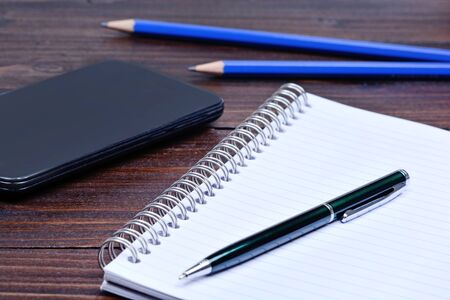 Notepad with pen telephone and pencils on desk close-up