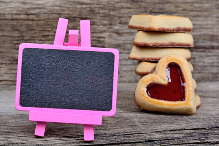 Pink small blackboard with heart cookies on wooden tableの写真素材