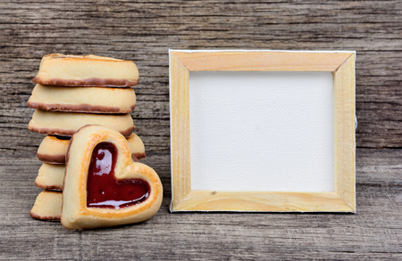 Empty frame with heart cookies on wooden tableの写真素材