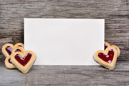 Empty paper with heart cookies on wooden tableの写真素材