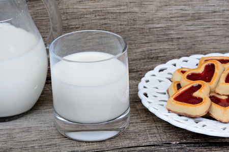 Glass of milk with heart cookies in a plate on table close-upの写真素材