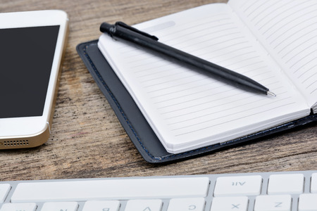 Office desk with keyboard computer, agenda and phone closeup