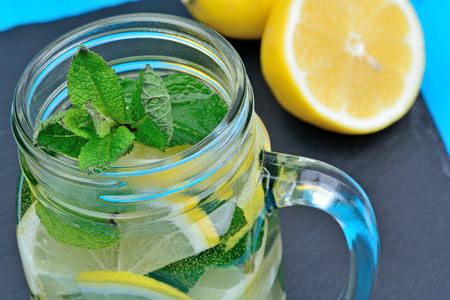 Close up of tasty beverage with lemon and mint on slateの写真素材
