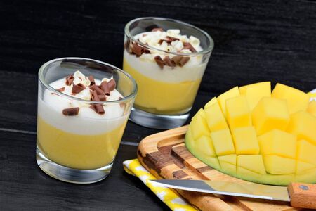 Mousse of mango in a glasses on black wood tableの写真素材