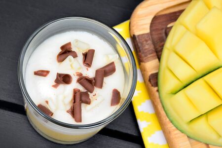 Mousse of mango fruit and chocolate in a glass jar on a wood tableの写真素材