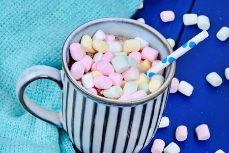 Hot chocolate with mini colorful marshmallow in a cup on wooden tableの写真素材