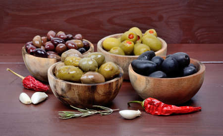 Olives in the wooden bowls with spicy on the wood tableの写真素材