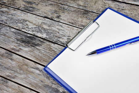 Close up of clipboard with blank white paper and pen on a wooden backgroundの写真素材