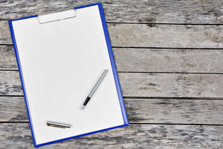 Clipboard with blank white paper with fountain pen on a wood table